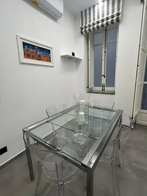a glass table in an empty room with chairs at Granatelli Apartment in Palermo