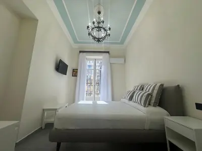 a bedroom with a bed with a chandelier and a window at Granatelli Apartment in Palermo