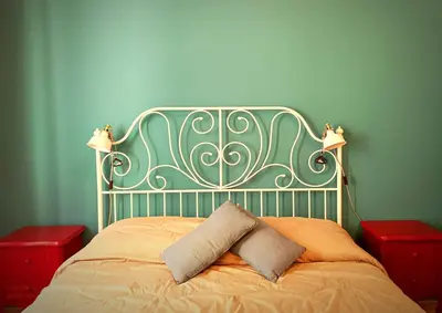 a bed with a green headboard with a pillow on it at Casa Cutó near Central Station in Palermo