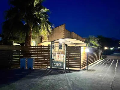 a building with a gate and a palm tree at night at Villa Stromboli - Le Ville del Mediterraneo in Campofelice di Roccella