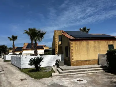 a house with a white fence and palm trees at Villa Stromboli - Le Ville del Mediterraneo in Campofelice di Roccella
