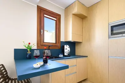 a kitchen with a blue counter with two glasses of wine at Hotel Calliope in San Vito lo Capo