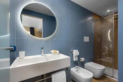 a bathroom with a sink and a toilet and a mirror at Hotel Calliope in San Vito lo Capo
