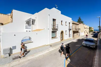 a group of people walking down a street next to a white building at Hotel Calliope in San Vito lo Capo