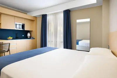 a hotel room with a large bed and a kitchen at Hotel Calliope in San Vito lo Capo