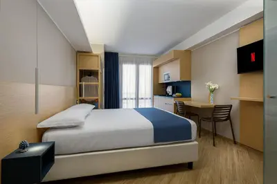 a bedroom with a bed and a desk and a kitchen at Hotel Calliope in San Vito lo Capo