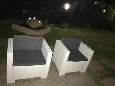 two wicker chairs sitting next to a fountain at night at Pine Beach House - Villaggio Turistico con Piscina e Animazione in Campofelice di Roccella