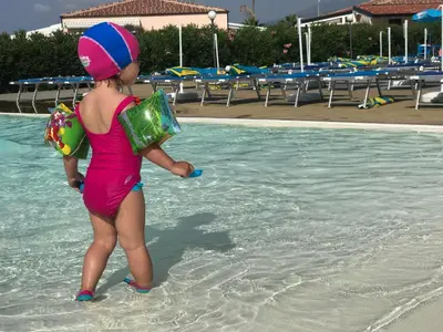 a young girl standing in the water at a swimming pool at Pine Beach House - Villaggio Turistico con Piscina e Animazione in Campofelice di Roccella