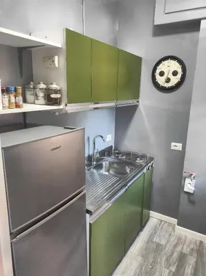 a kitchen with green cabinets and a sink and a clock at Central Apartment Cavour in Palermo