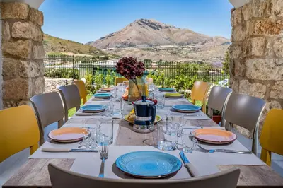a long table with plates and wine glasses on a patio at Villa Coraline in Castellammare del Golfo