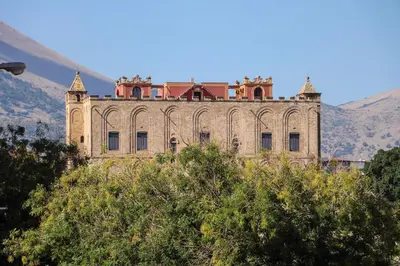 an old building on a hill with mountains in the background at La Dimora di Guglielmo Tourist Rental in Palermo