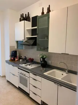 a kitchen with white cabinets and a sink and a stove at Da Nonna Marié in Palermo