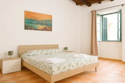 a white bedroom with a bed and a window at Cattedrale - Vicolo Brugnò in Palermo