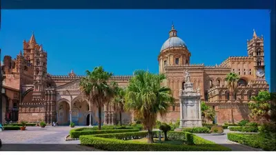 a large building with a clock tower and palm trees at Ughetti Apartment in Palermo