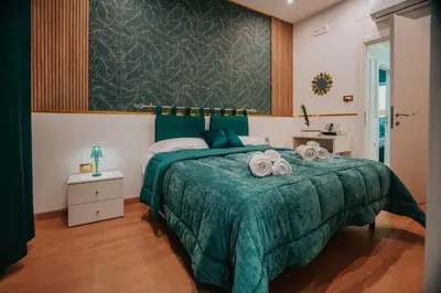 a bedroom with a green bed with towels on it at Cama Luxury Rooms in Palermo