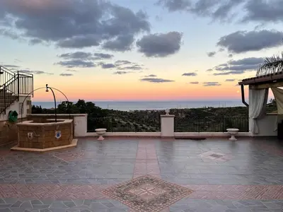 a building with a gate and a palm tree at night at Tenute Armani The Castle Live an Experience in Altavilla Milicia