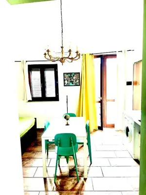 a kitchen with a table and a green chair at Via del Bosco Home in Palermo