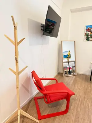 a red chair and a television in a room at Dimora dell'Olivella 1 in Palermo