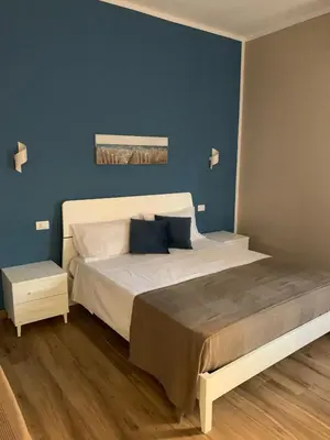 a bedroom with a large bed with a blue wall at Titti's Room in Casteldaccia