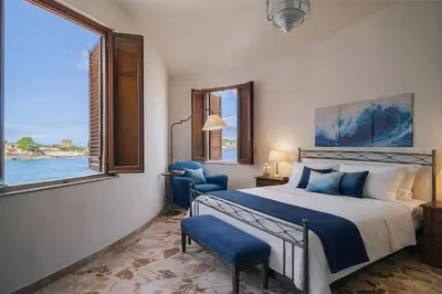 a bedroom with a bed and a chair and a window at LeSicilien - Tilde Sunset Bay Villa in Carini