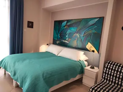 a bedroom with a green bed with a painting on the wall at B&b Bagheria in Bagheria
