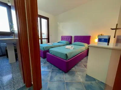two beds in a room with purple furniture at Casa Sterlizia by Holiday World in San Vito lo Capo