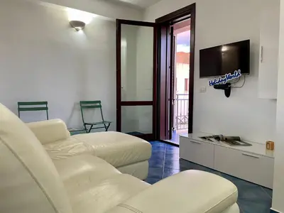 a living room with two white chairs and a flat screen tv at Casa Sterlizia by Holiday World in San Vito lo Capo