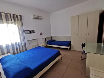 a bedroom with a blue bed and a desk at Case d'estate Mondello in Palermo