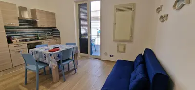 a living room with a table and a blue couch at Casa Fortuna Mondello in Palermo
