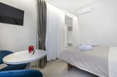 a white room with a bed and a table and a tv at Case libertà in Palermo
