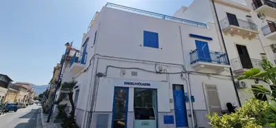 a white building with blue doors on a street at Casa Elisa in Palermo