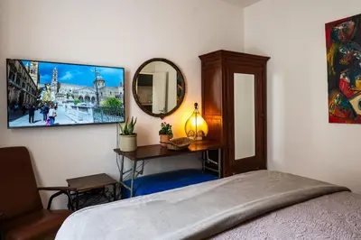 a bedroom with a bed and a mirror and a table at Terrace in the Sky overlooking Historic Center in Palermo
