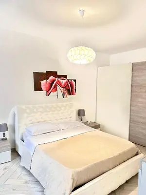 a white bedroom with a large bed and a chandelier at Bandiera's House in Palermo
