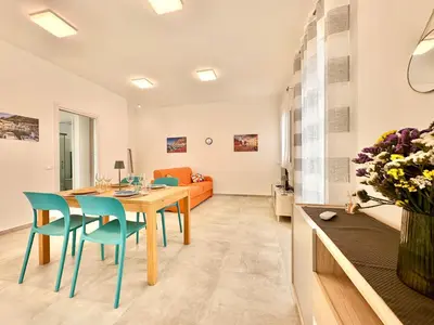 a dining room and living room with a table and chairs at Zàgave Apartment a 200 mt dal mare in Alcamo