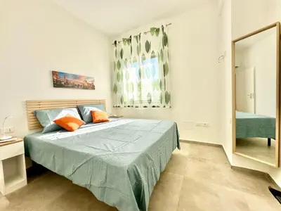 a bedroom with a bed with blue sheets and orange pillows at Zàgave Apartment a 200 mt dal mare in Alcamo