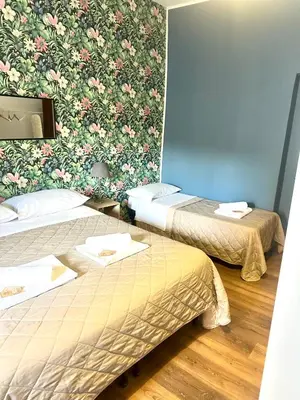 two beds in a room with a floral wallpaper at Porta di Castro's Home in Palermo