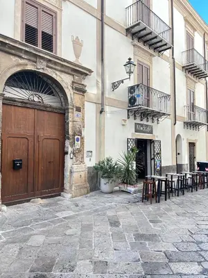 a building with a wooden door and tables and chairs at Dimora dell'Olivella 2 in Palermo