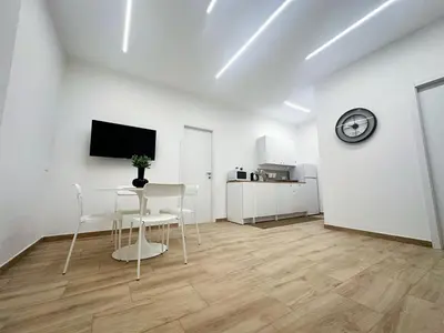 a white room with a table and chairs and a clock at Daimana holiday apartament in Palermo