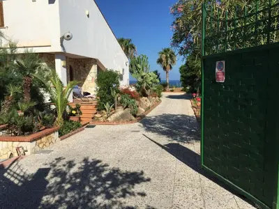 a driveway leading to a house with a green gate at Apartment Villa Gina in Trappeto by Interhome in Trappeto