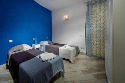 a room with two beds and a blue wall at APT RINO Sea View basement in Villa Rosaria in Scopello