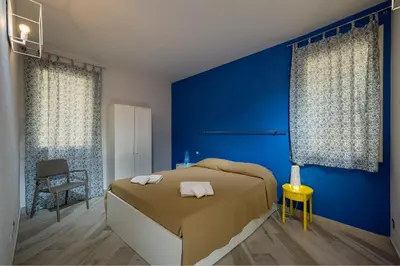 a blue bedroom with a bed and a chair at APT RINO Sea View basement in Villa Rosaria in Scopello