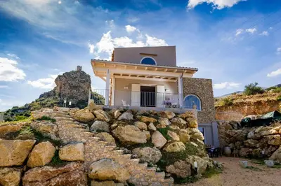 a house on top of a pile of rocks at APT RINO Sea View basement in Villa Rosaria in Scopello