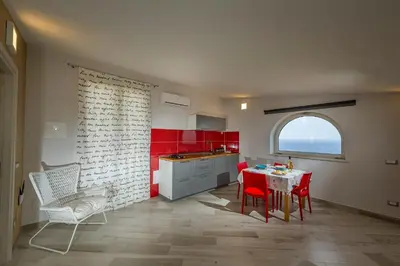 a kitchen with red cabinets and a table and chairs at APT NINO in Villa Rosaria Vista Mare Zingaro in Scopello