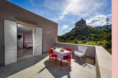 a room with a table and chairs on a balcony at APT NINO in Villa Rosaria Vista Mare Zingaro in Scopello