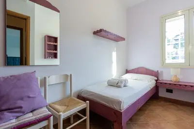 a bedroom with a bed and a chair and a mirror at Visitsicilia Sabbia Dorata in Alcamo Marina