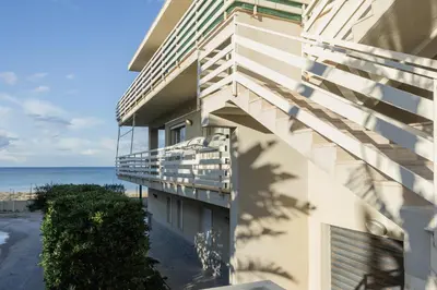 a building with a balcony with the ocean in the background at Visitsicilia Sabbia Dorata in Alcamo Marina