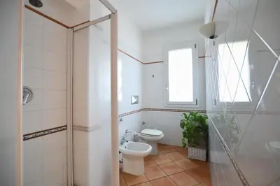 a white bathroom with a toilet and a window at iFlat Punta Catalana in Terrasini