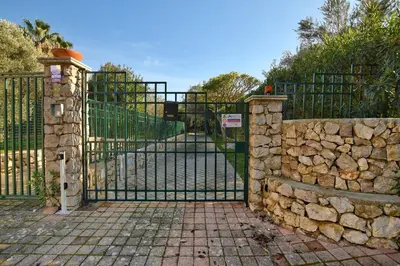 an iron gate with a stone fence and a stone wall at iFlat Punta Catalana in Terrasini
