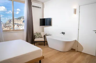 a bathroom with a tub and a bed and a tv at Skyline Boutique Hotel in Palermo