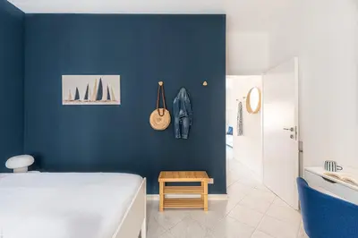 a bedroom with a blue wall with a bed and a stool at Ludohome in Palermo